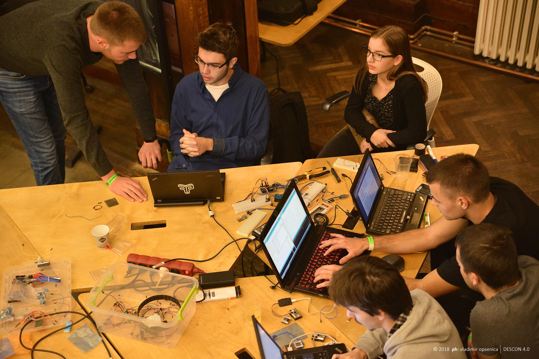 Radna atmosfera sa laptopovima za stolom tokom hakatona